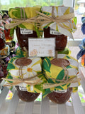 Jars of Waimānalo Meli lemon & ginger honey with yellow floral fabric lids on a white shelf